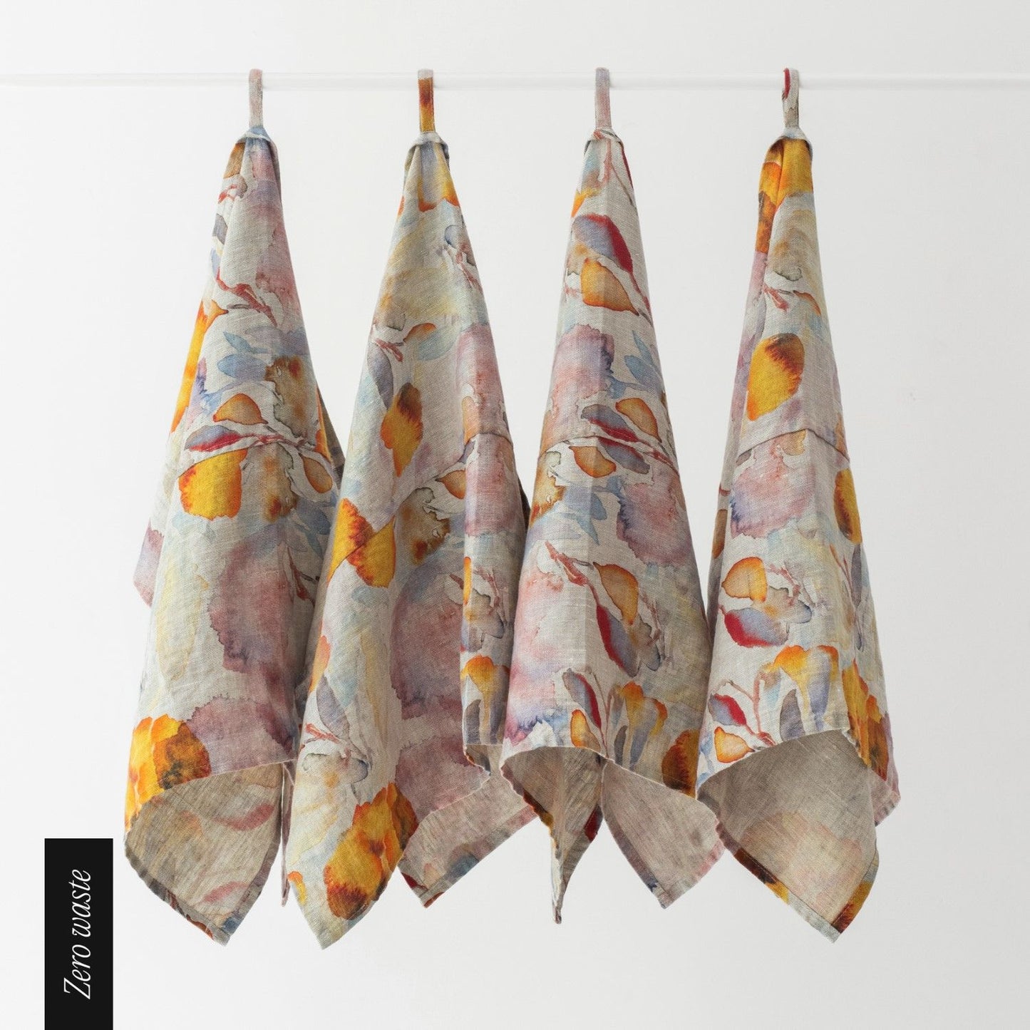 Kökshanddukar med orange och rött mönster hänger på en ställning.