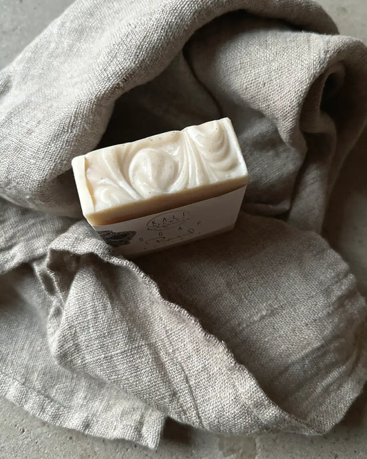 En vit tvål med textur och en beige linnehandduk.