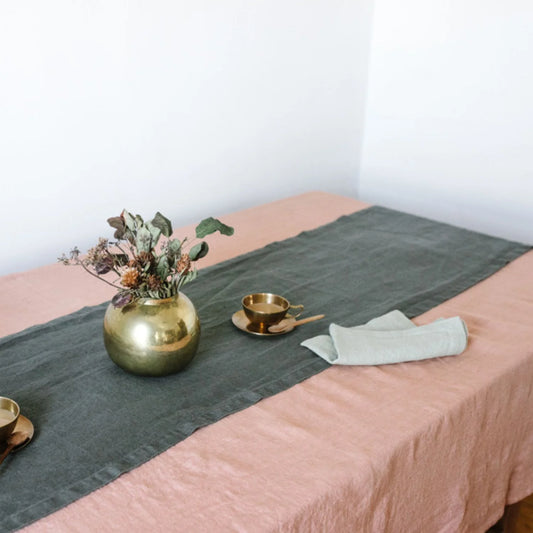 En skogsgrön linnelöpare liggandes på en aprikos duk.