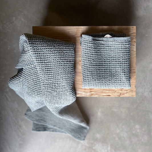 Två ljusblå linnehanddukar ligger på en träbänk