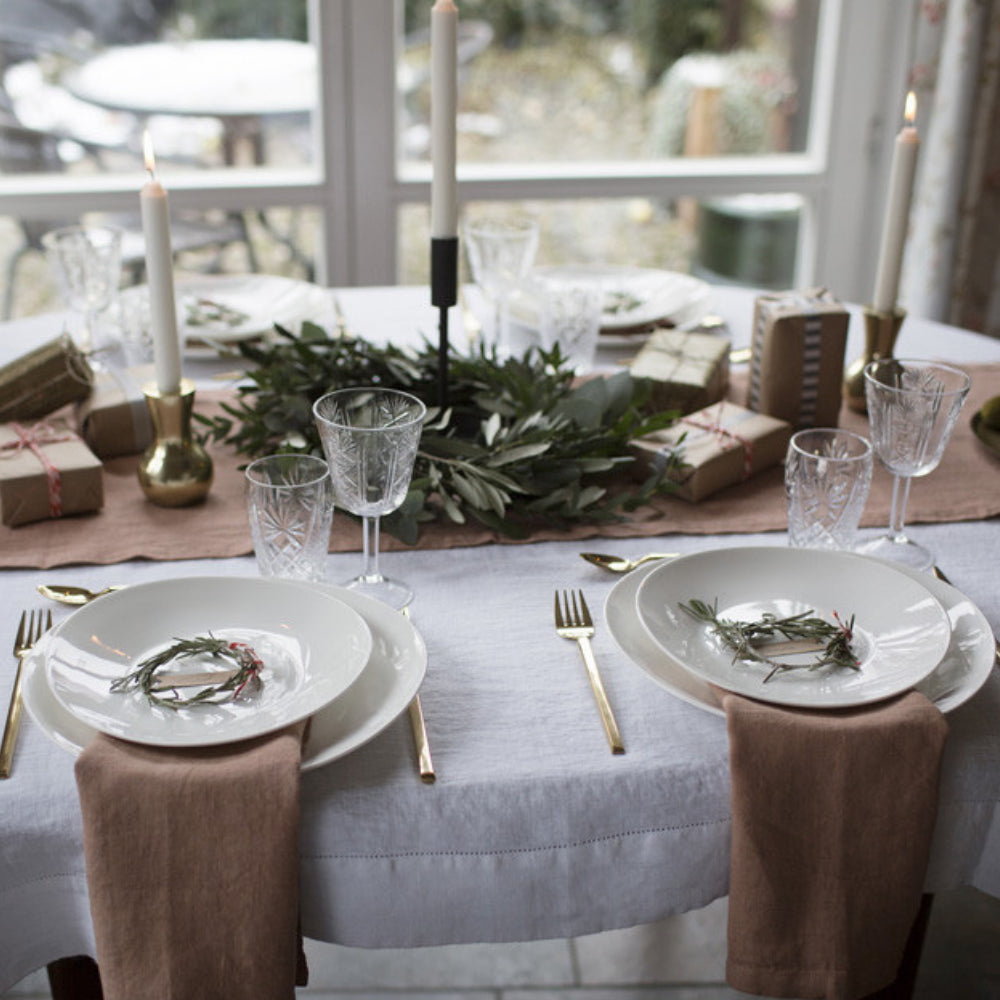 Ett dukat bord med vita och creme färgade linnetextiler.
