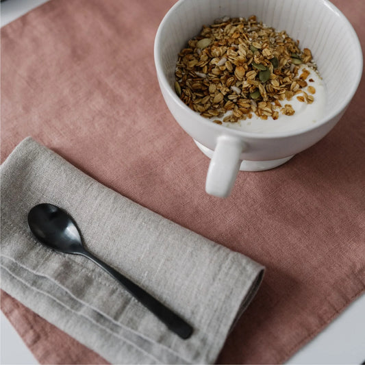 Beige tygservett ligger på en aprikosfärgad bordstablett.