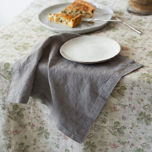 En grå tygservett på en blommig linneduk.