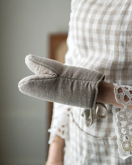 En mindre grytskydd i linne med ögla för upphängning