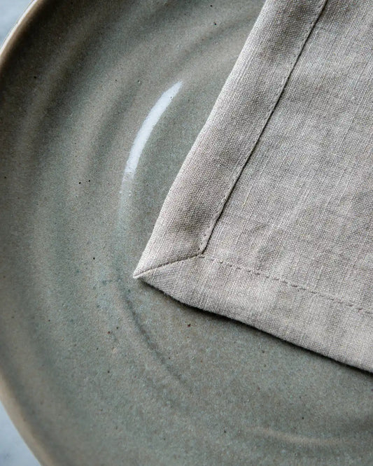 Beiga linneservetter med dekorativa hörn.