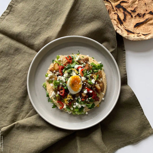 En olivgrön handduk ligger under en tallrik.