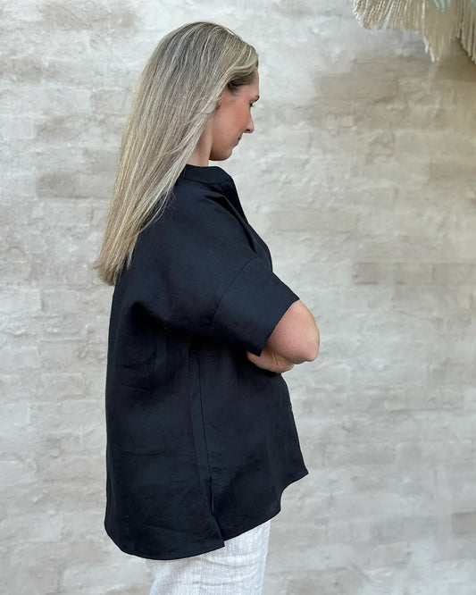 Modell bär en svart linneblus med kort ärm