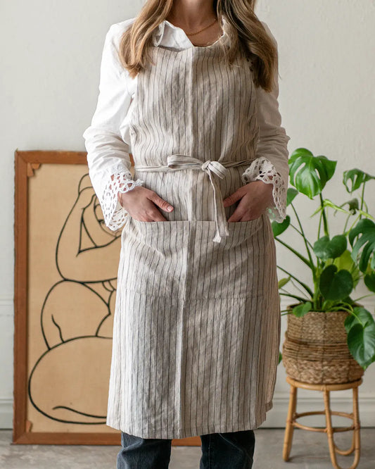 Ett kritstrecksrandigt förkläde med band och fickor