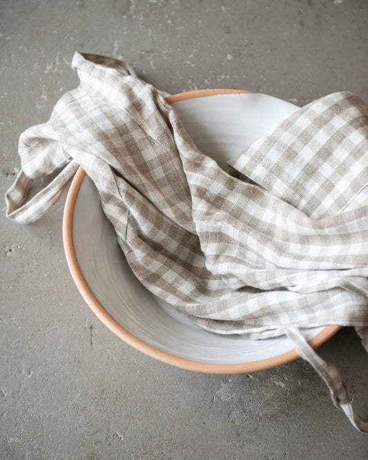 Ett rutigt förkläde ligger i en handdrejad keramikskål