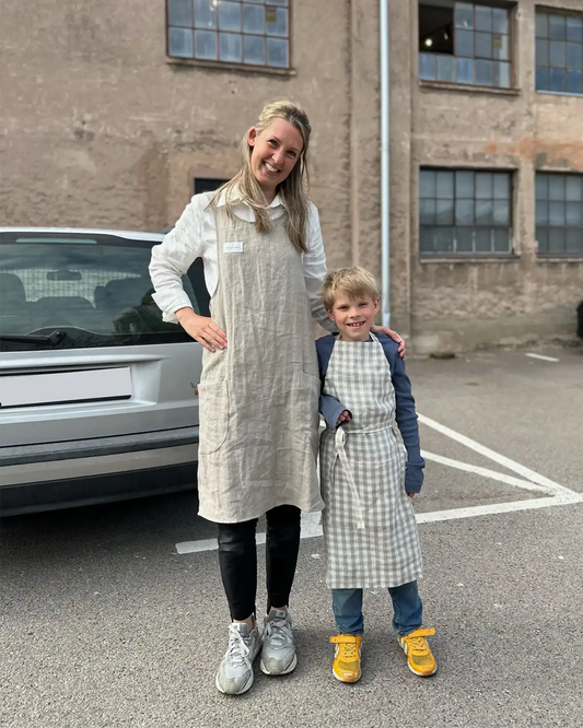 Pojke och tjej har på sig köksförkläde i linne.