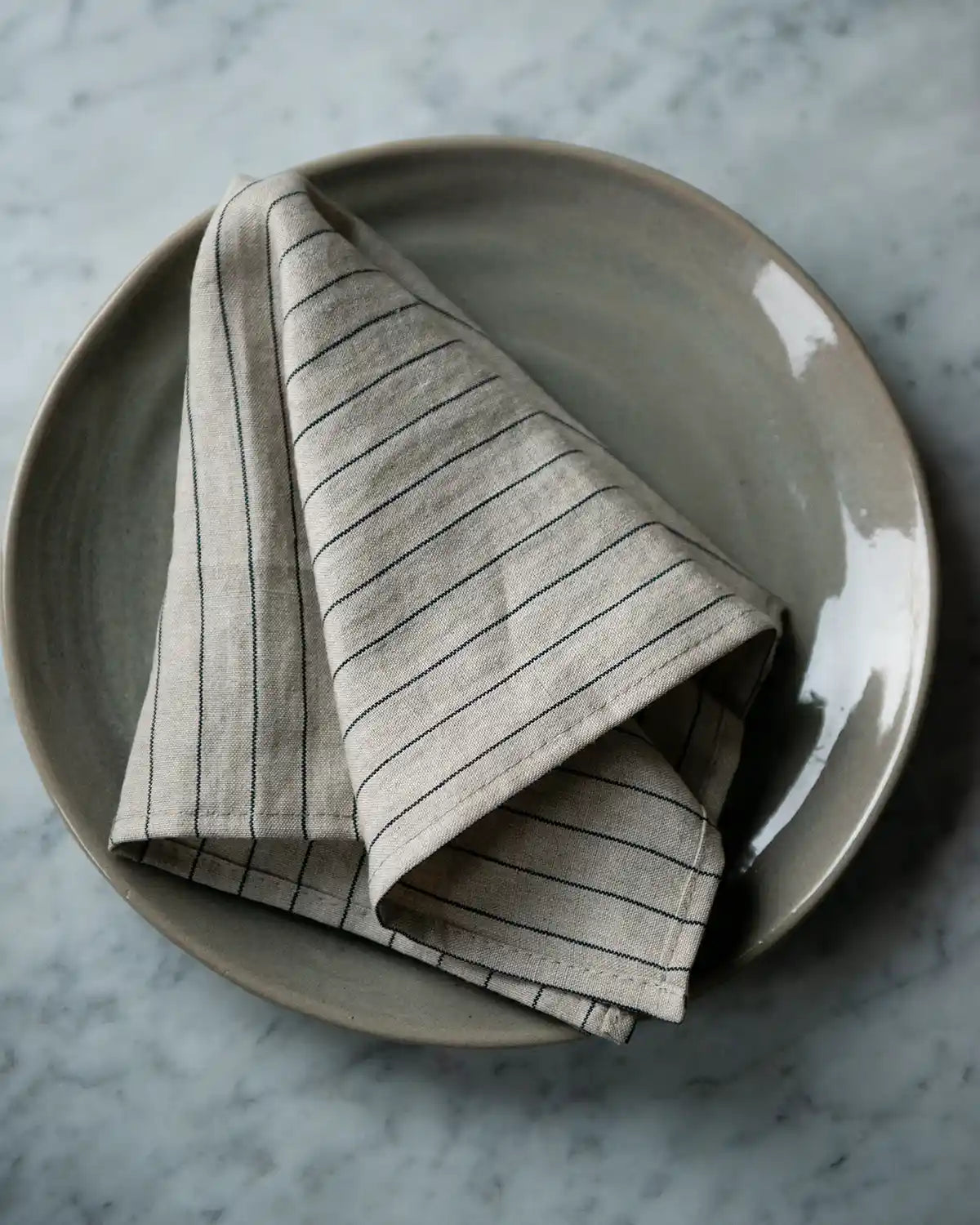 En kritstrecksrandig linneservett.