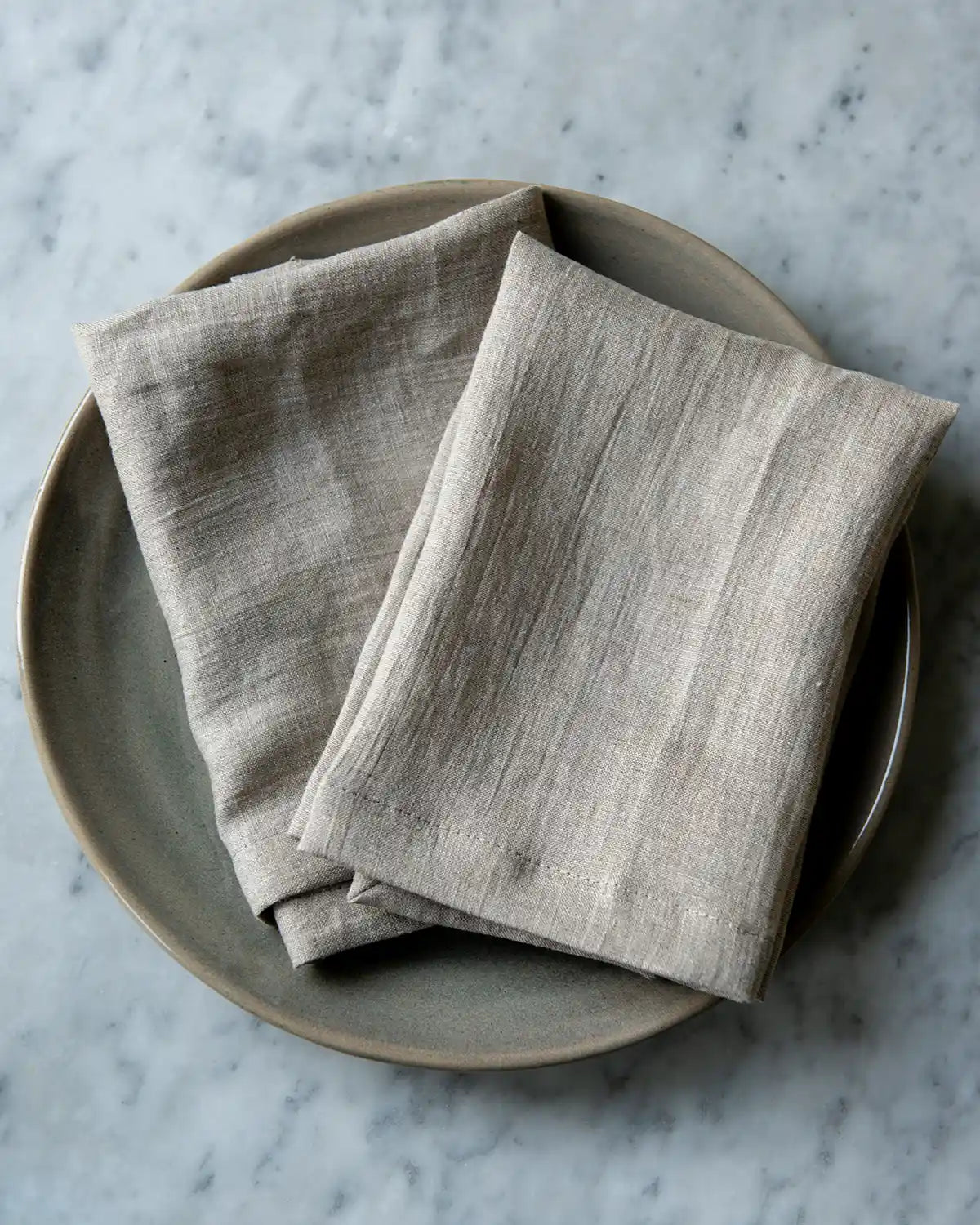 Linnefärgade tygservetter på en beige tallrik
