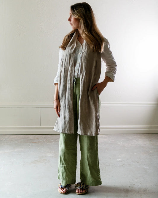 En kvinna med gröna och vita linnekläder och en beige linnesjal