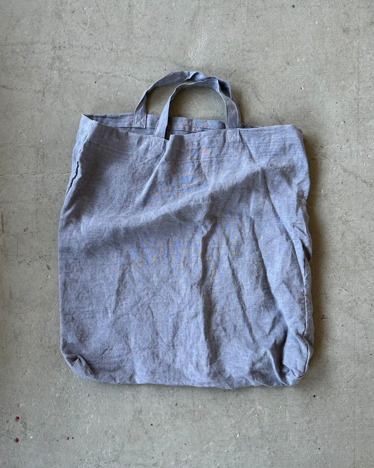 En gråblå påse i linne med korta handtag