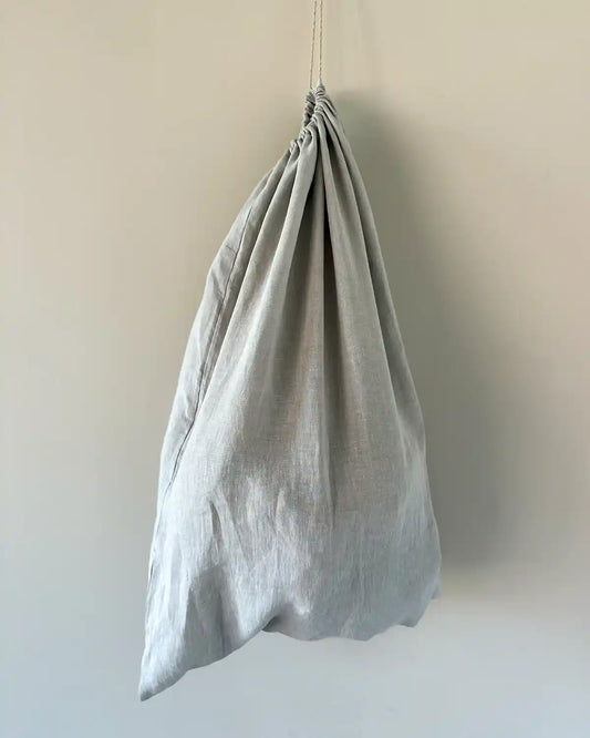 En stor tvättpåse i ljusgrå linne.