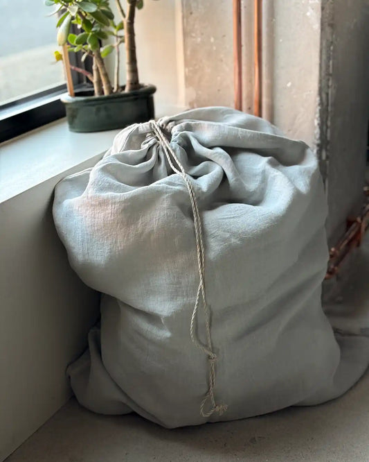 En ljusgrå tygpåse med dragsnöre.