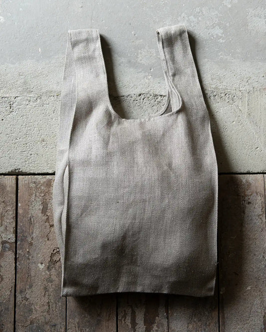 En sandfärgad tygpåse i linne med breda handtag