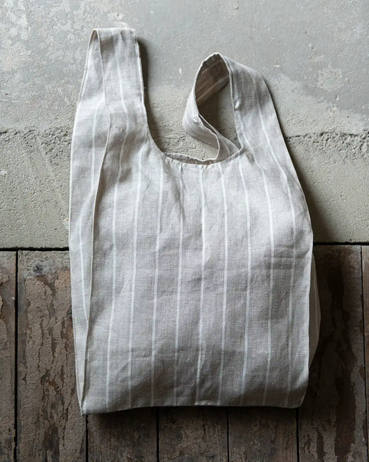 En randig tygpåse med tunna ränder ligger på ett golv