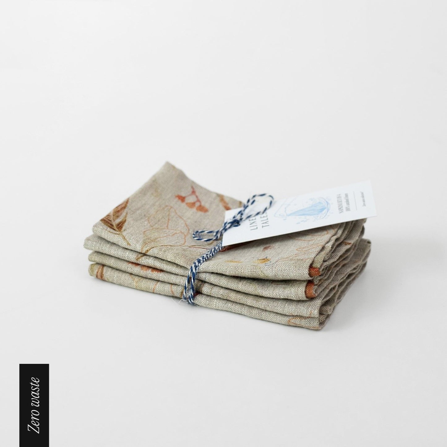 Fyra stycken beiga linneservetter med löv mönster.