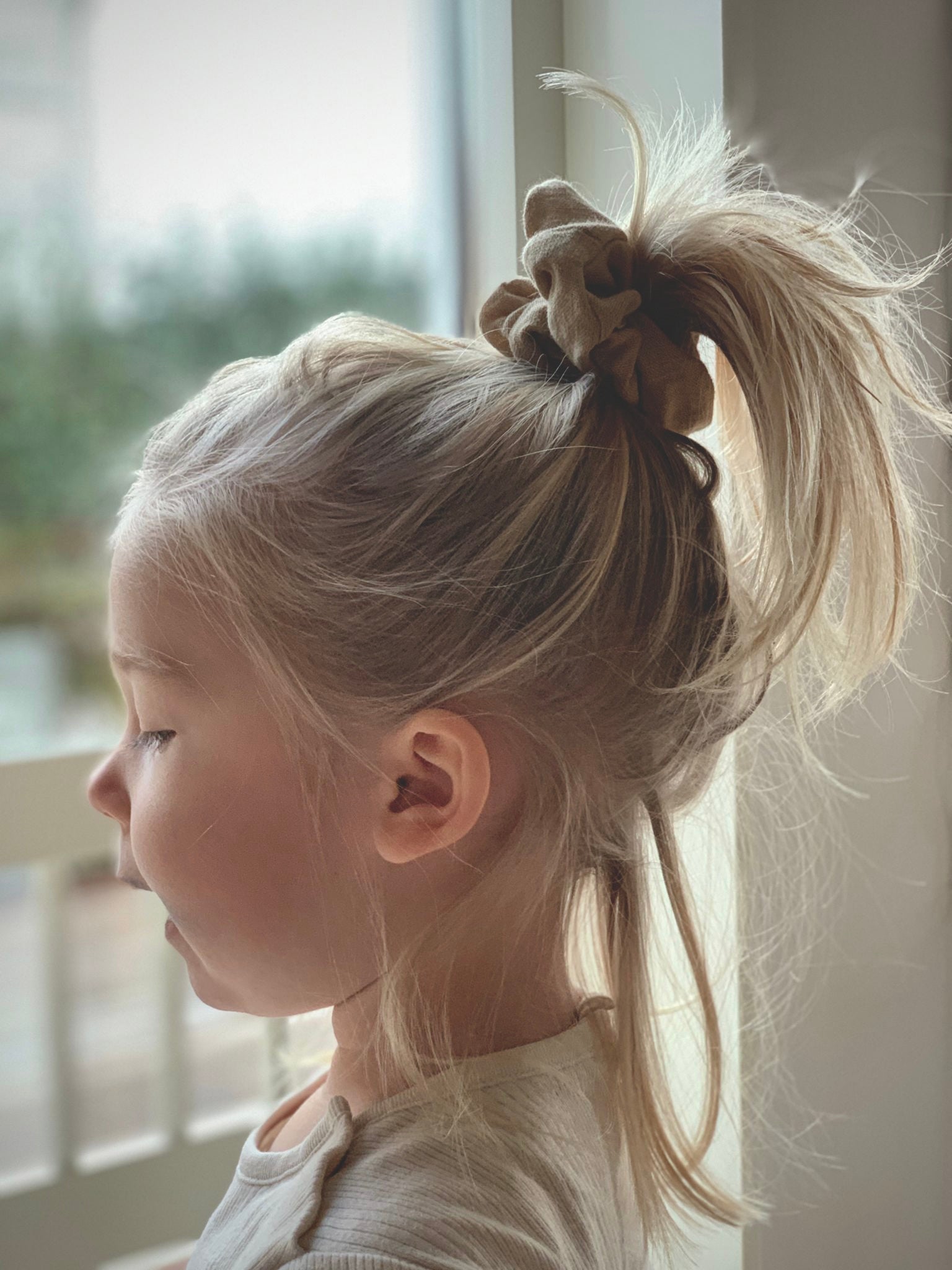 Flicka har uppsatt hår i en handsydd scrunchie i linnetyg