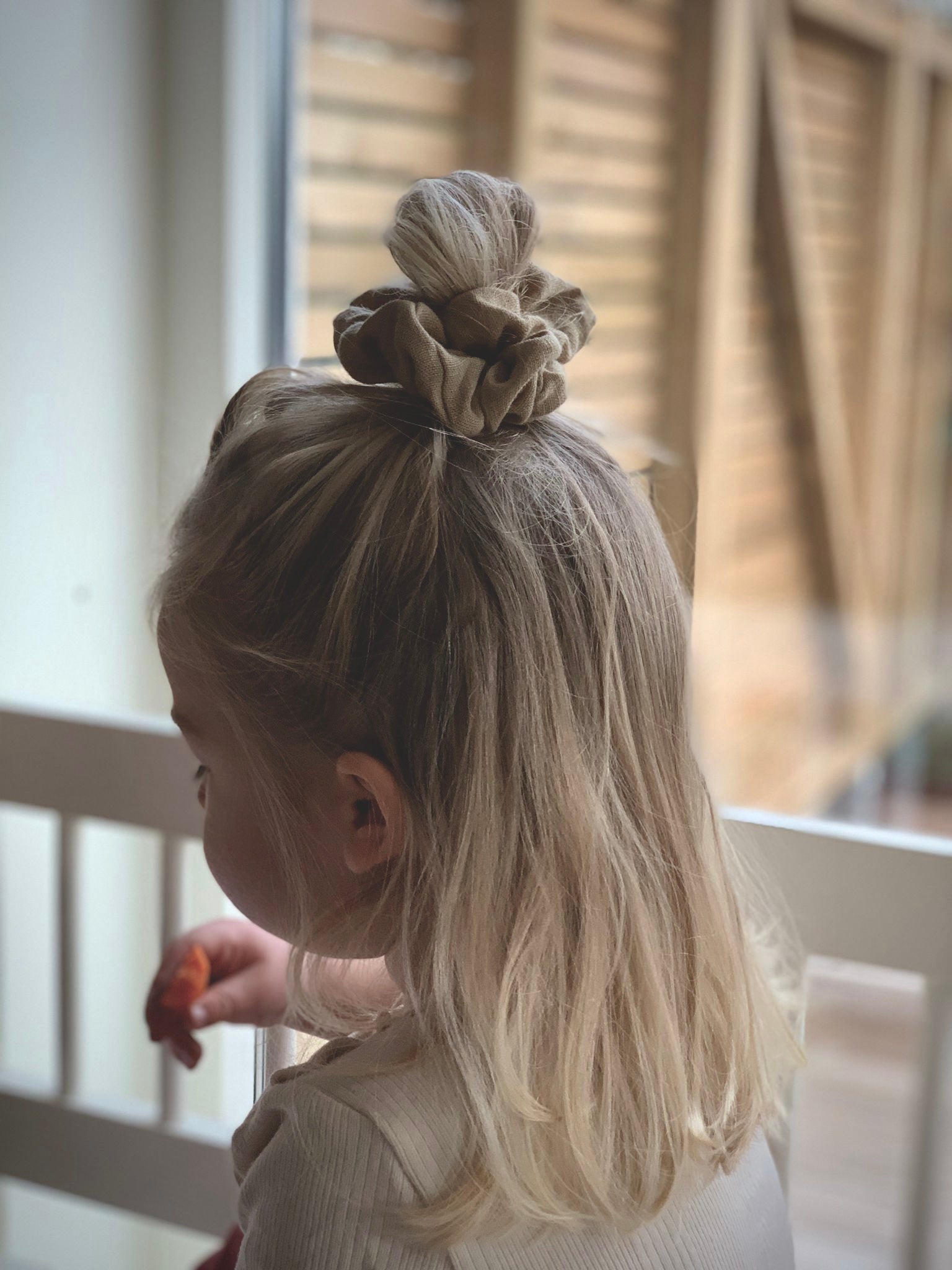 Person bär en scrunchie i linne som är handsydd.