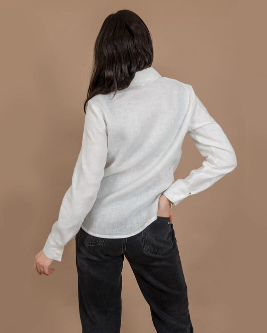 En kvinna bär en vit klassisk vit figursydd linneskjorta.