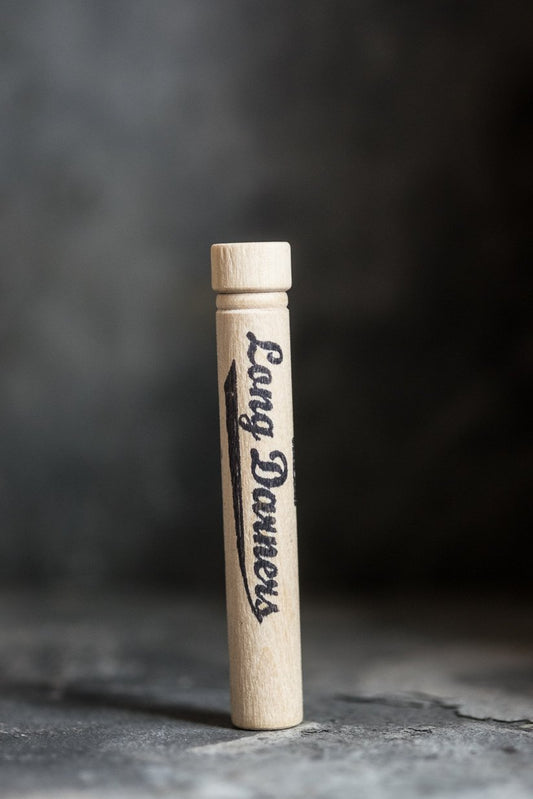 En liten rund förpackning i trä för lagningsnålar.