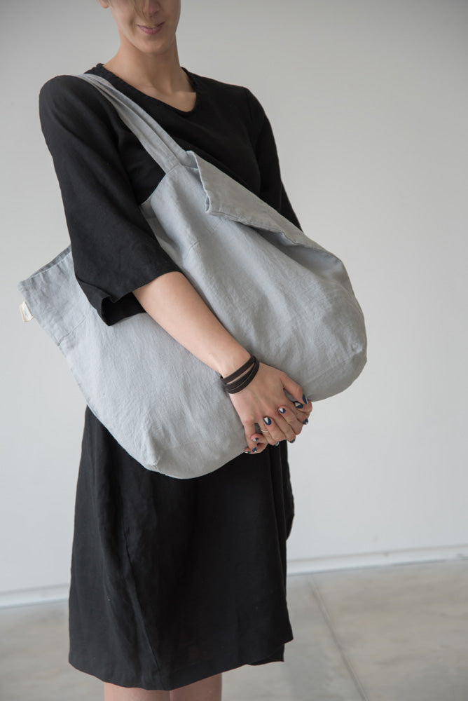 En kvinna bär en ljusgrå väska i linne.