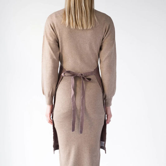 Ett rosa köksförkläde i linne med långa band som har knutits runt ryggen.