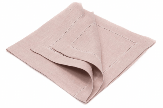 En lusrosa linneservett med hålsöm ligger ihopvikt.