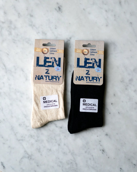 Två linnestrumpor i beige och svart ligger bredvid varandra på ett marmor bord.