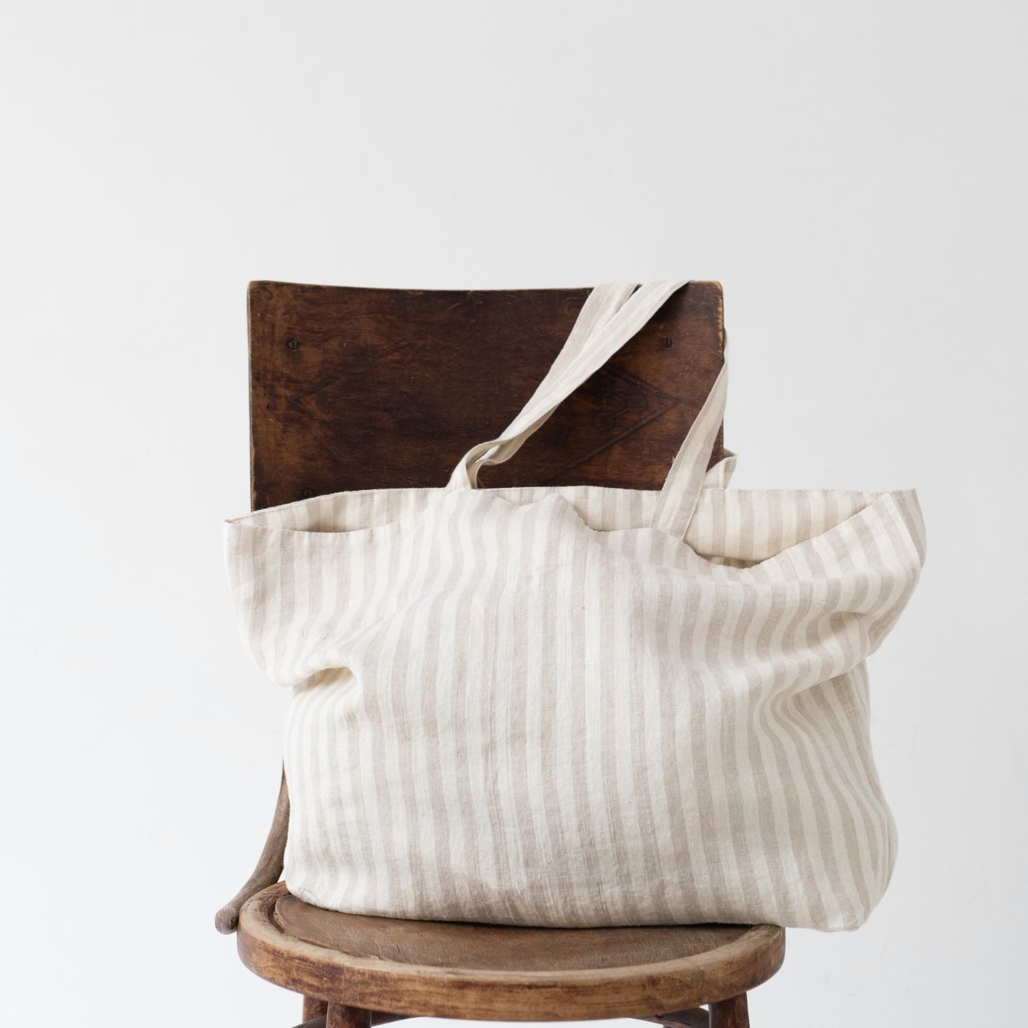 En tygpåse med vita och beige ränder linne står på en stol.