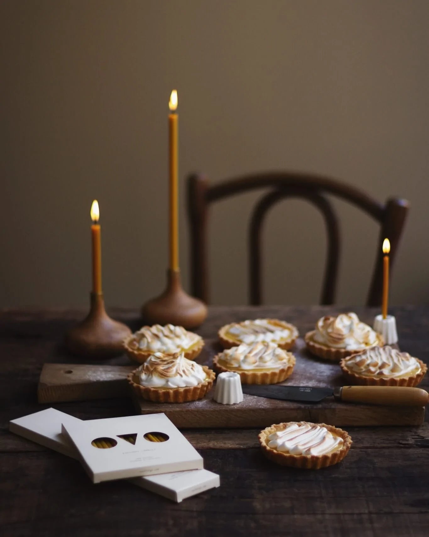 Olika storlekar på bivax ljus brinner i handgjorda ljusstakar av keramik och trä.