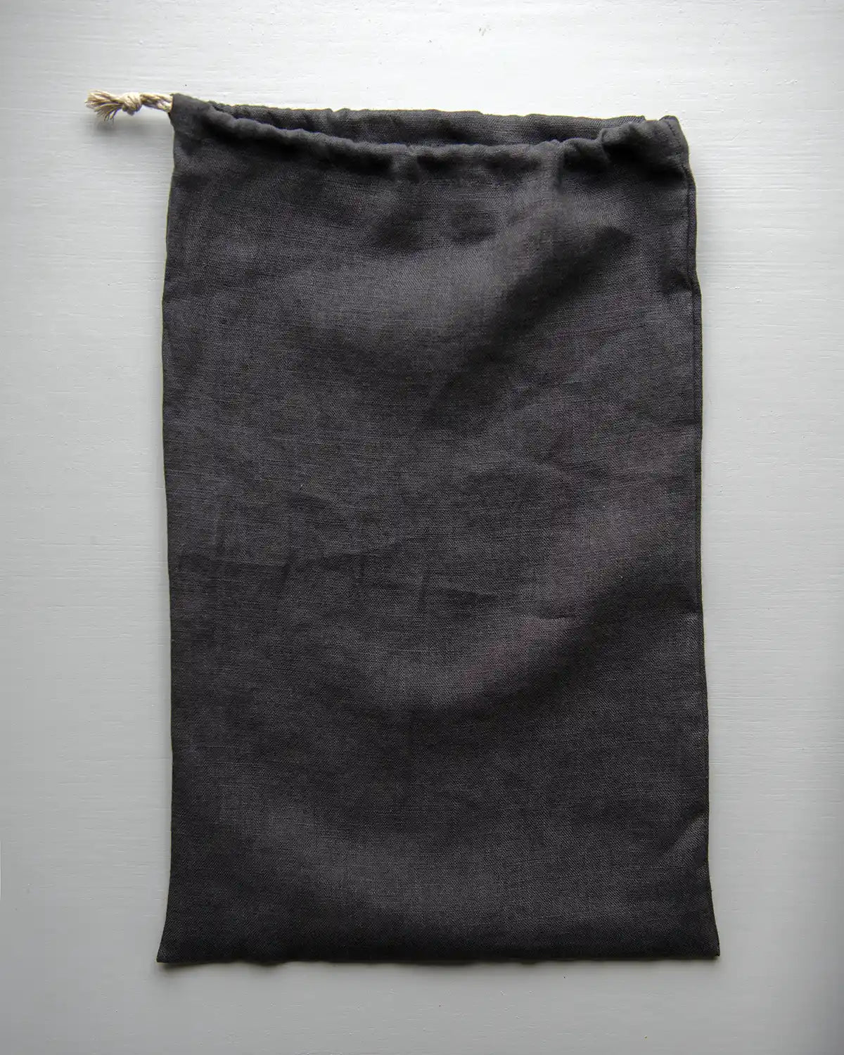 En handsydd brödpåse i mörkgrå linne.