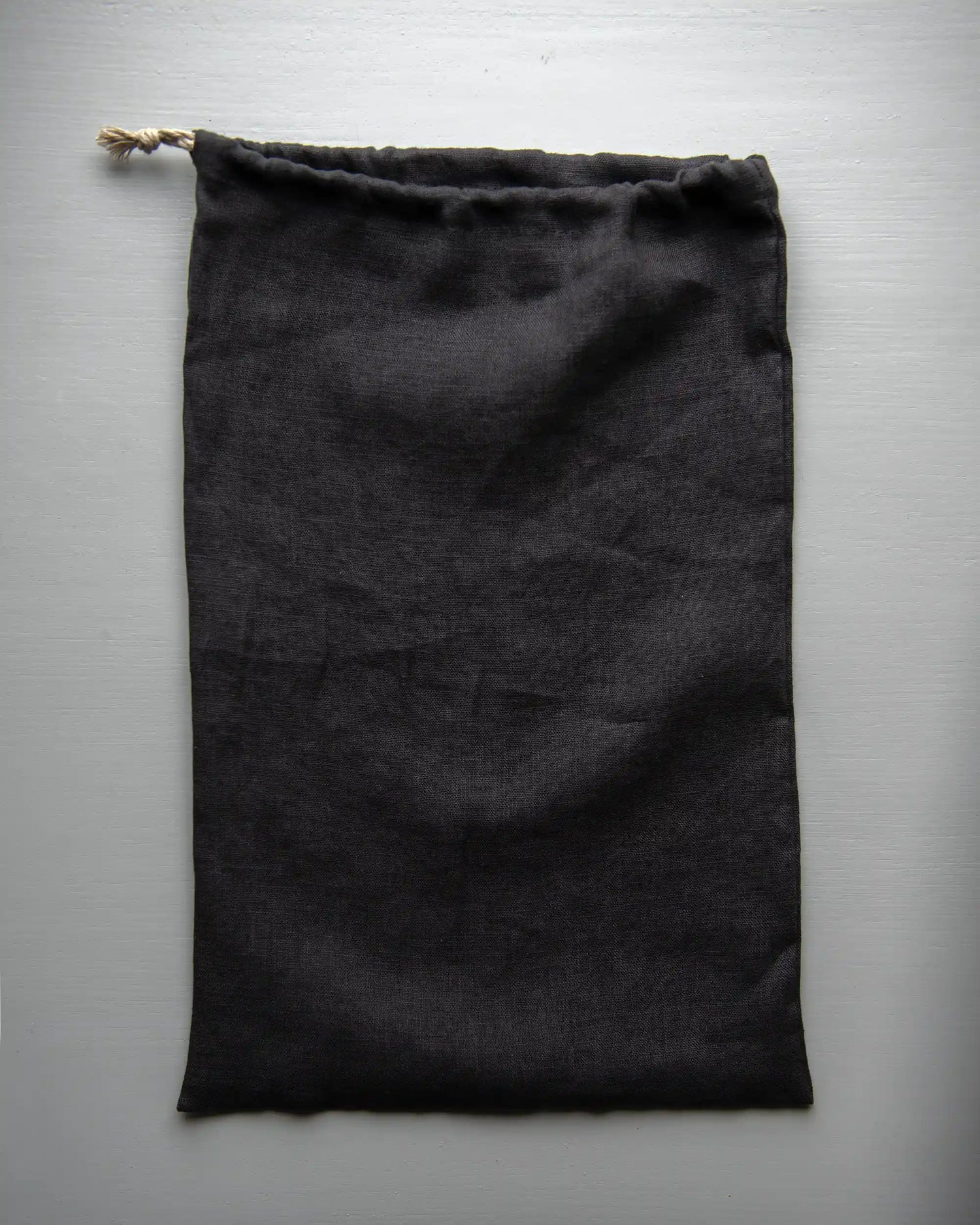 En handsydd brödpåse i mörkgrå linne.