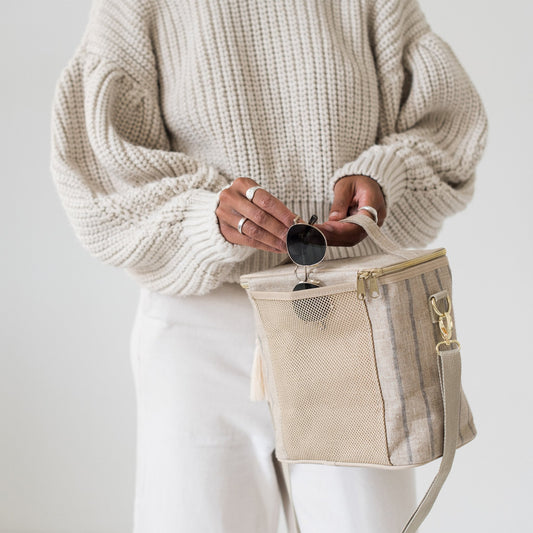 En kvinner håller i en medelstor kylväska i naturell linne med grå ränder.