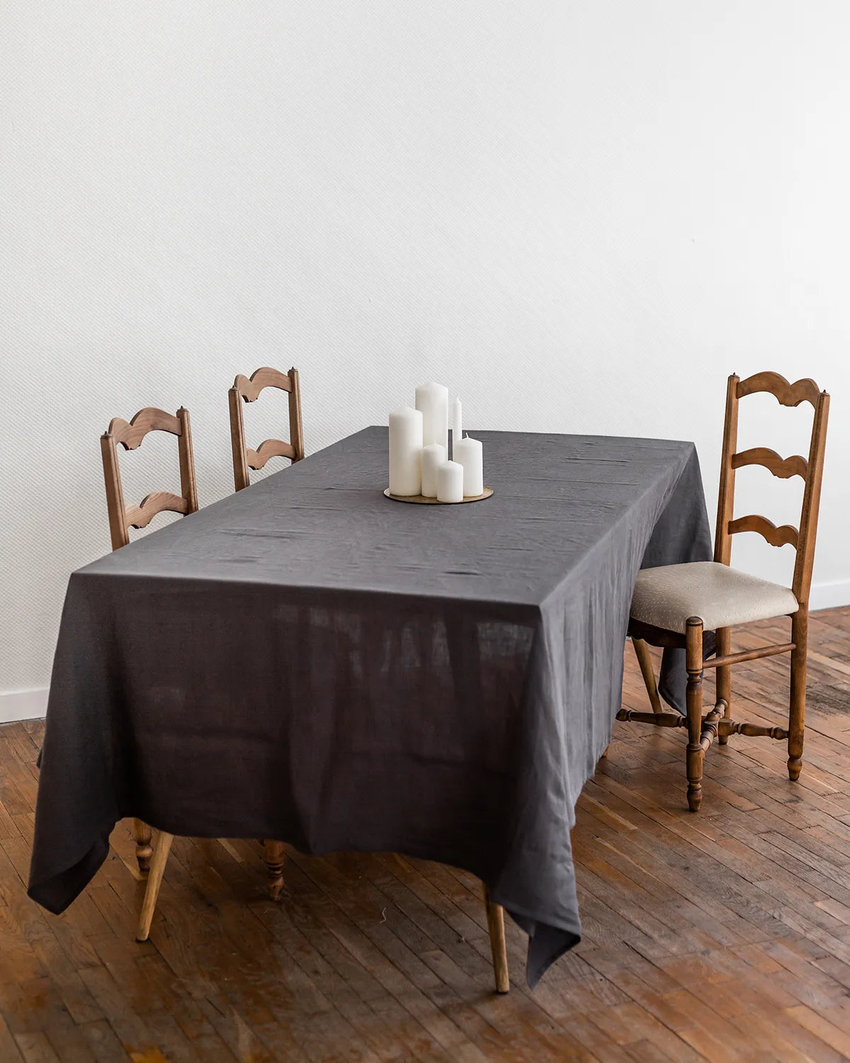 En mörkgrå rektangulär bordsduk i linne ligger på ett bord. 