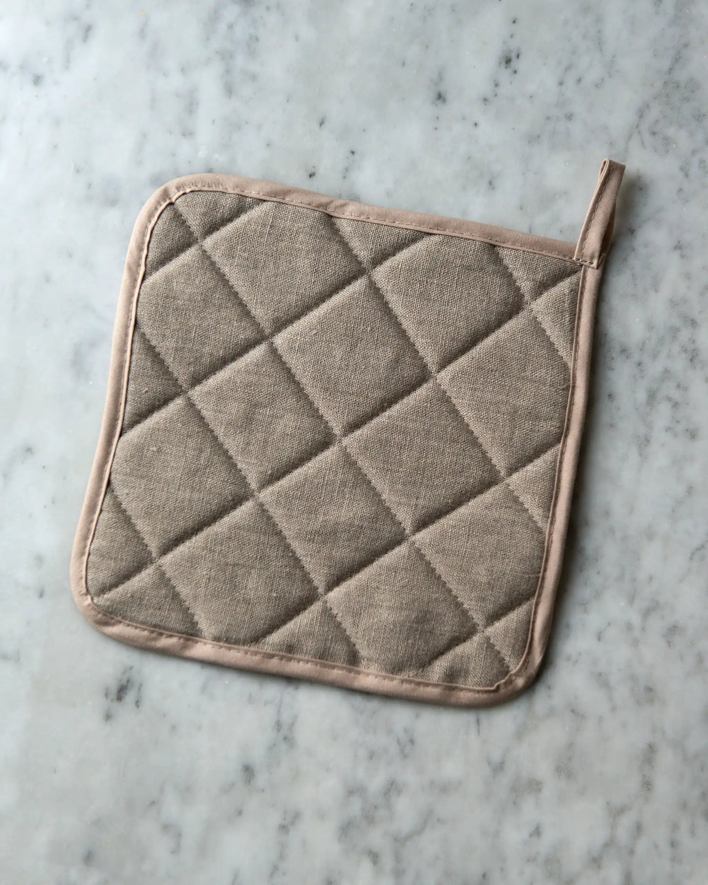 En handsydd beige grytlapp i linne.