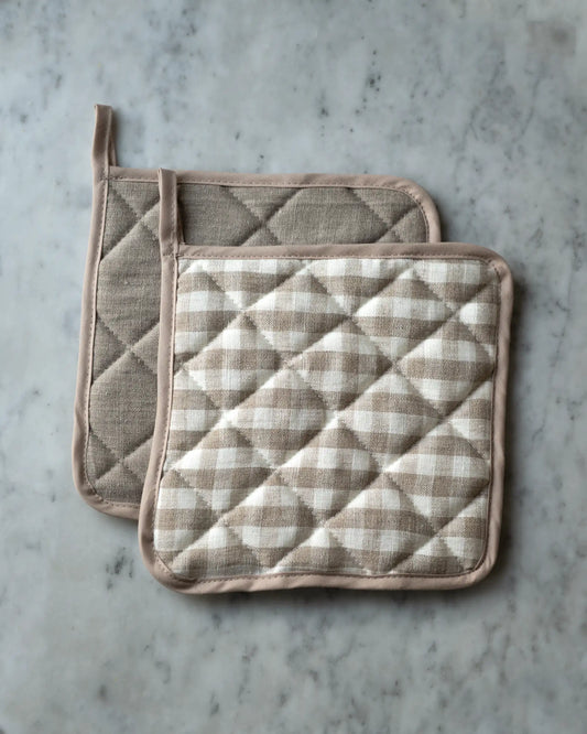 Två handsydda grytlappar i linne med beige ränder.