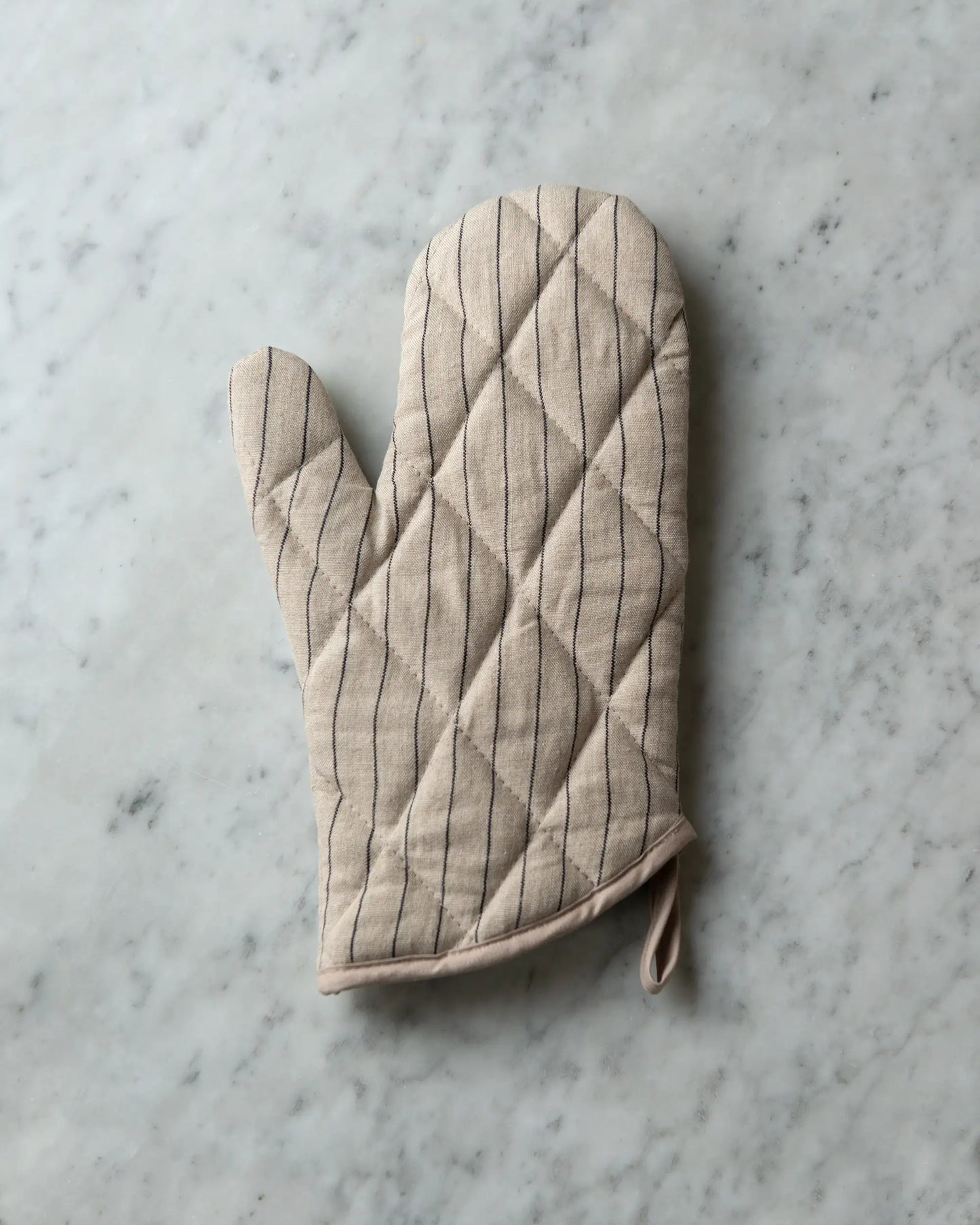 En handsydd grytvante i linne med tunna ränder i svart och beige.