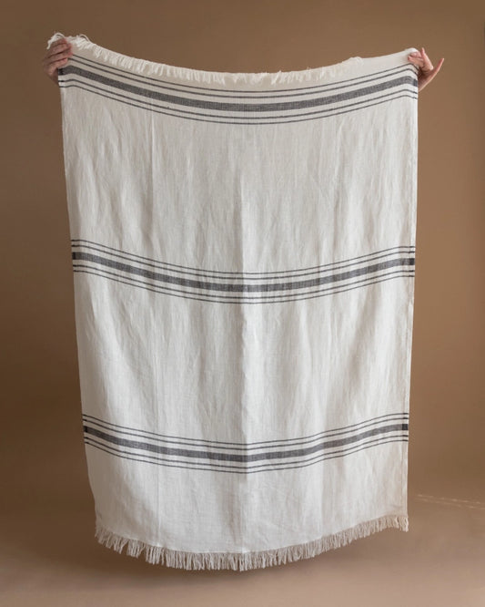 En hamamhandduk med ränder och fransar i vit linneblandning.