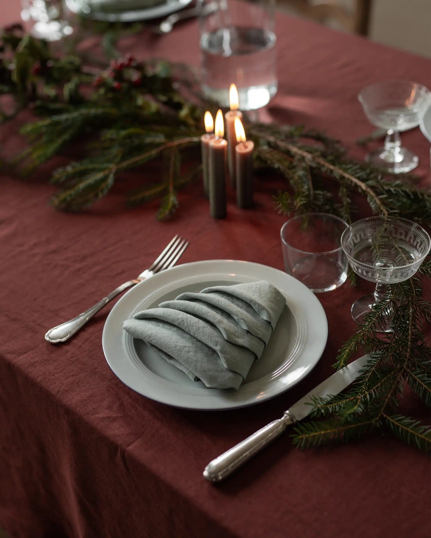 En ljusgrön linneservett som är vikt som en julgran ligger på en tallrik.