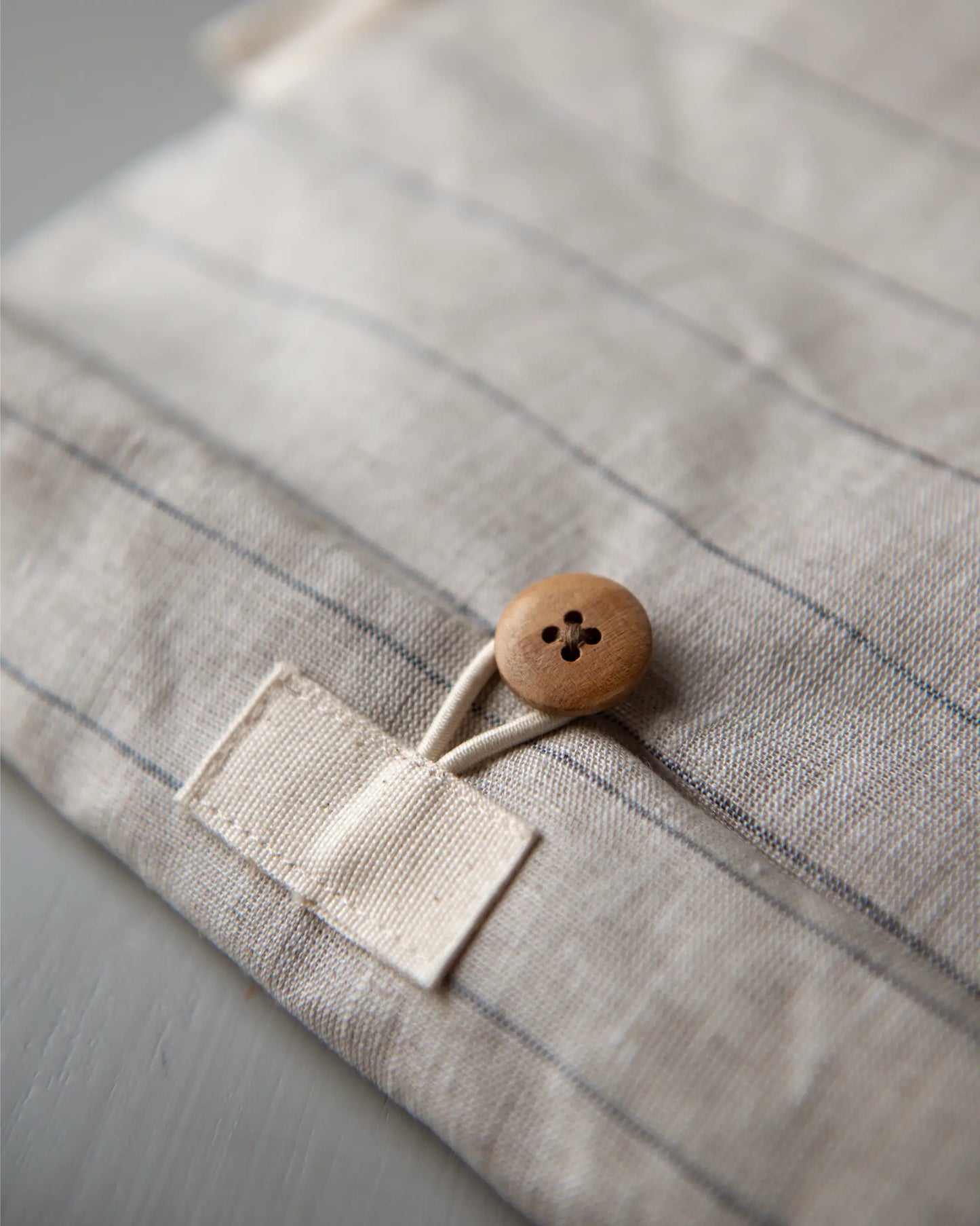 En handsydd lunchpåse i linne med dekorativ brun knapp.