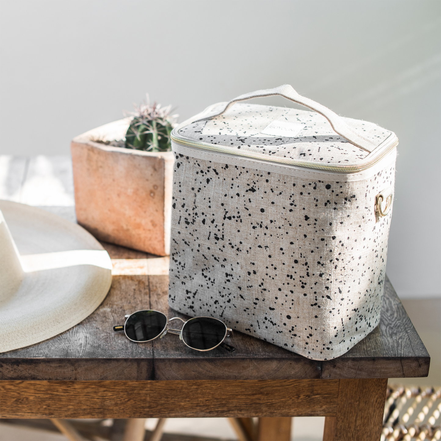 En beige handsydd lunchbox i linne med svart mönster.