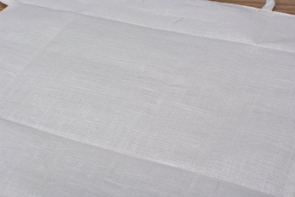 Brödkorg i vit linne ligger utvikt på en träyta. 