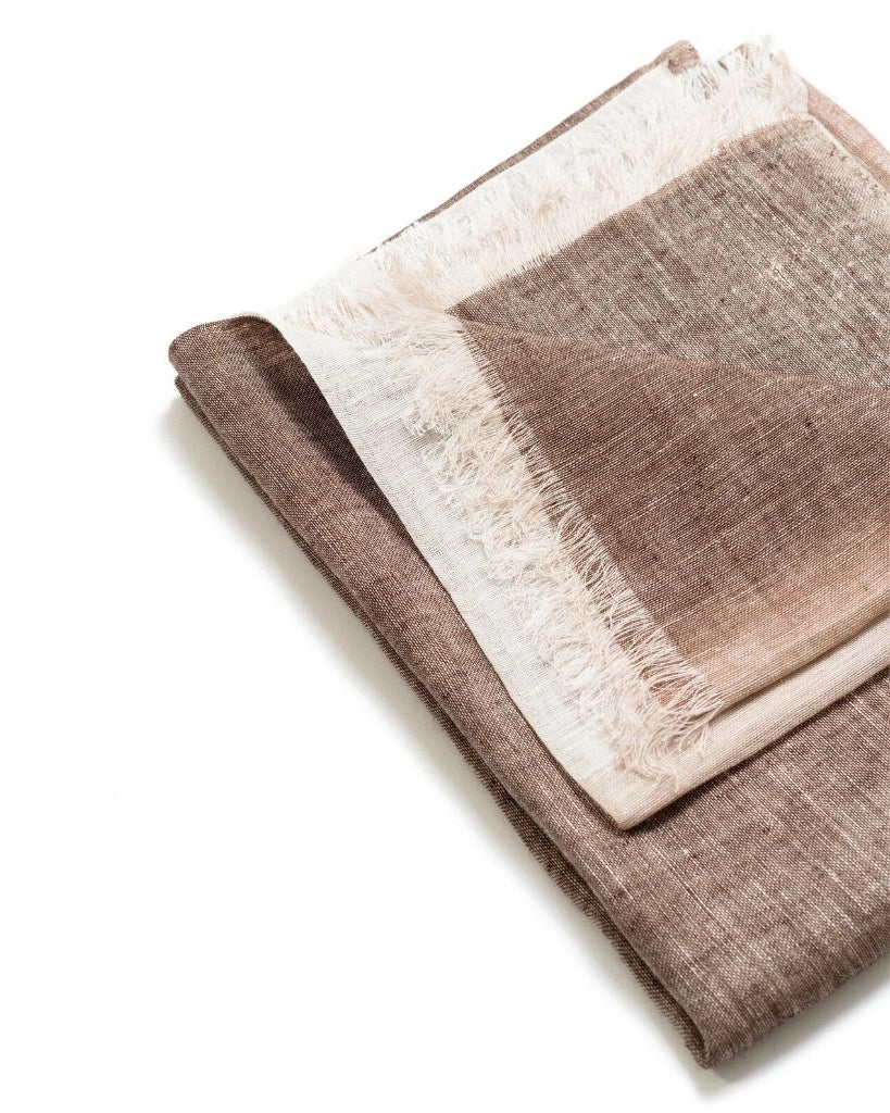 En handsydd linnesjal i brun och beige med fransar.