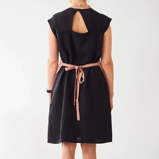 En person har knutit ett aprikosfärgat linneförkläde i ryggen.