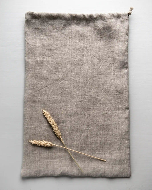 En rektangulär brödpåse i naturell linne ligger utan innehåll på en vit yta.