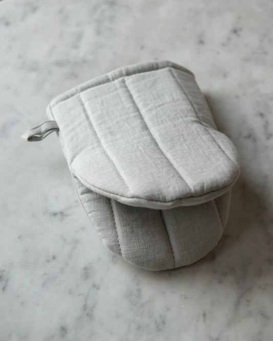 En ljusgrå handsydd grytvante i linne.