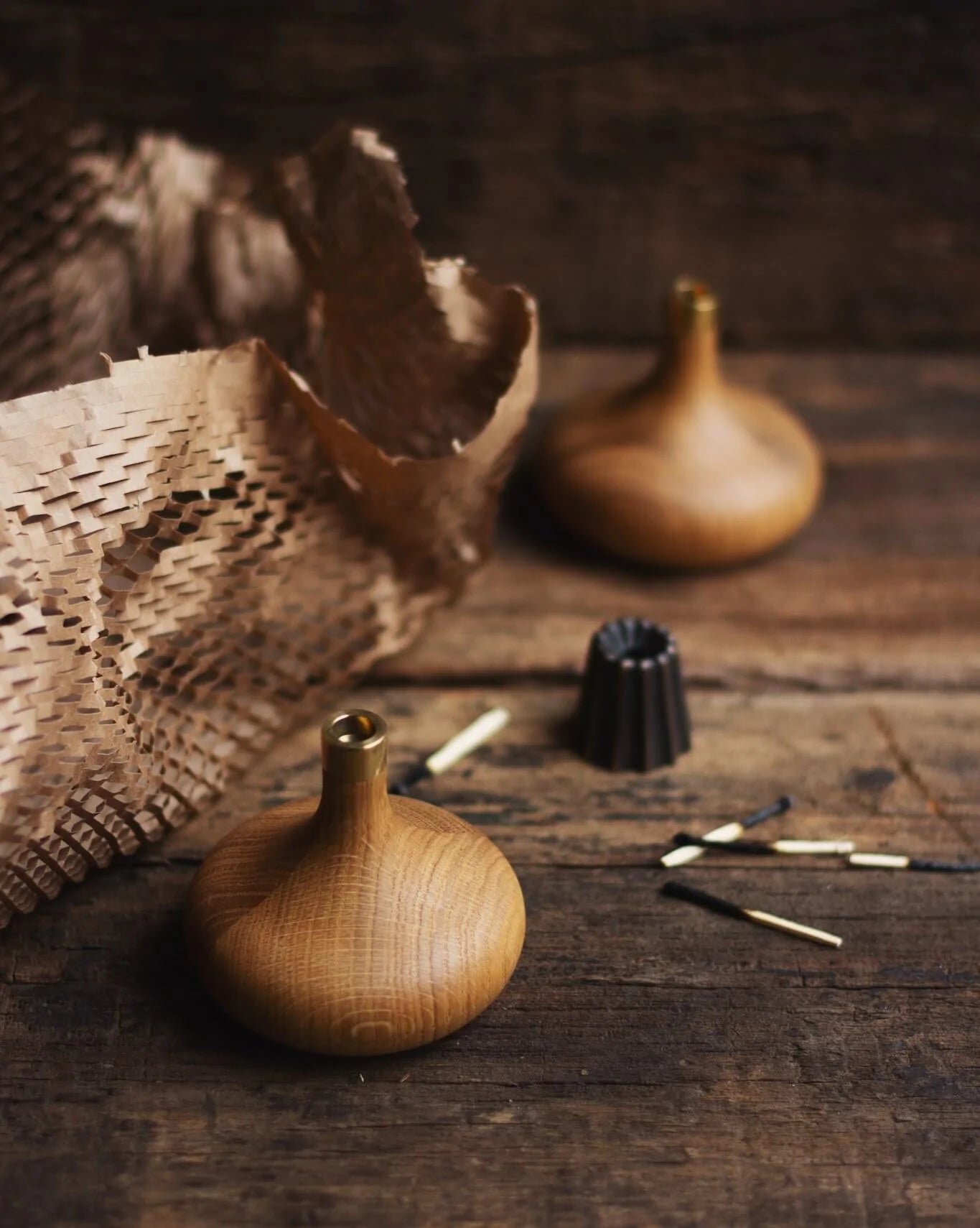 Två stycken handgjorda träljusstakar i oljad ek står på en träskiva. 